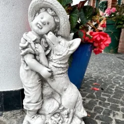 Betonskulptur af en dreng med en grå havefigur